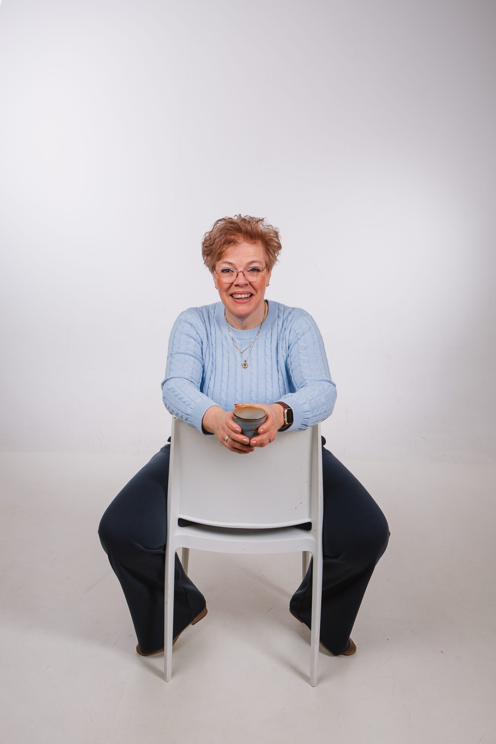 Marjolein zit op een stoel met een kopje koffie in haar hand